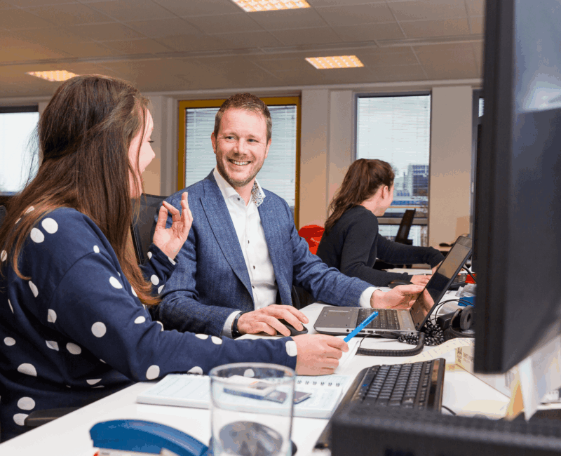 Werknemers achter hun bureau aan het overleggen en aan het praten met elkaar