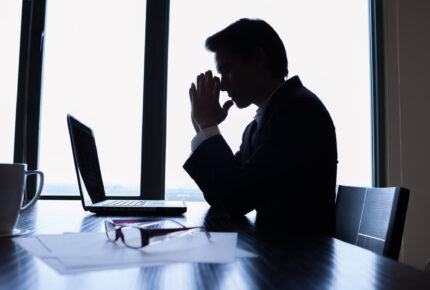 Een medewerker in de rouw, wat nu? 5 Mannelijke medewerker zit achter zijn laptop met zijn handen voor zijn gezicht | Rouw