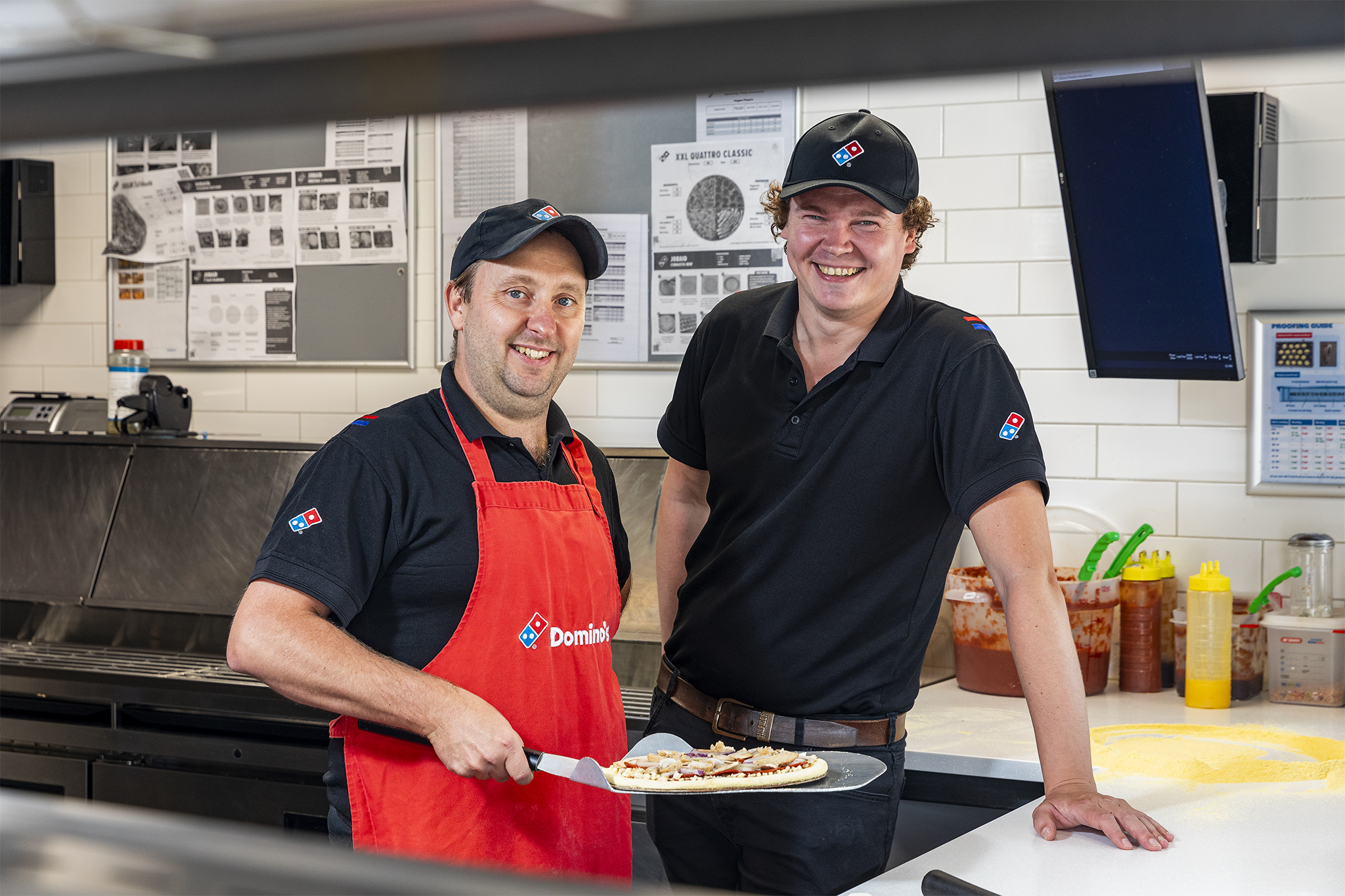 Medewerkers Domino aan het werk, pizza aan het bakken