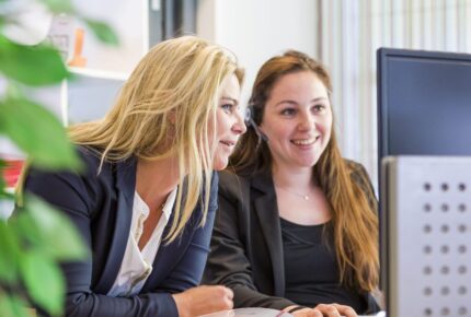 de 5 meest voorkomende misvattingen over payroll ontkracht 4 2 vrouwelijke collega's die aan het overleggen zijn achter de computer | Kosten payroll